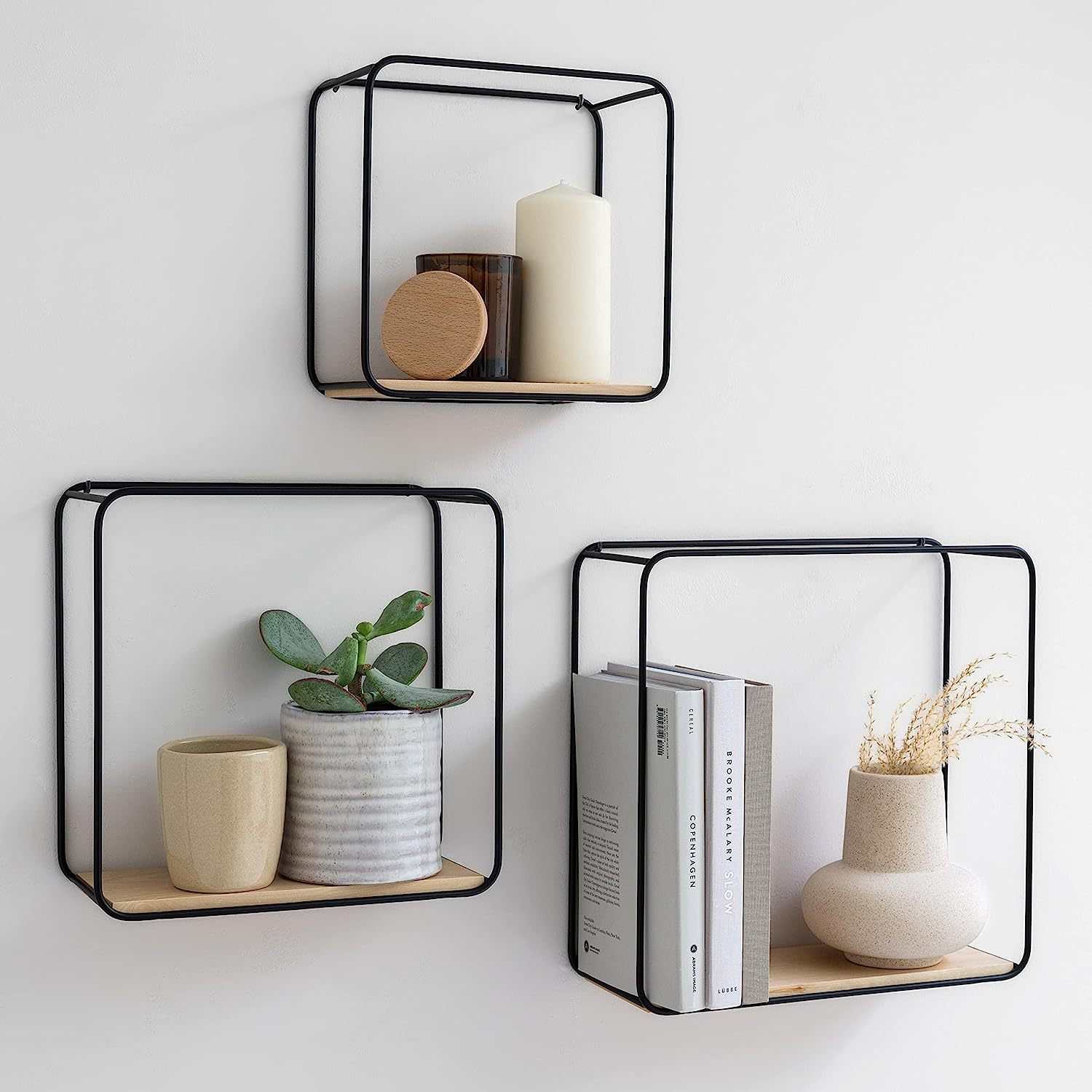 Stylish black wall shelves displaying candles, plants, and books, enhancing Home Improvement decor.